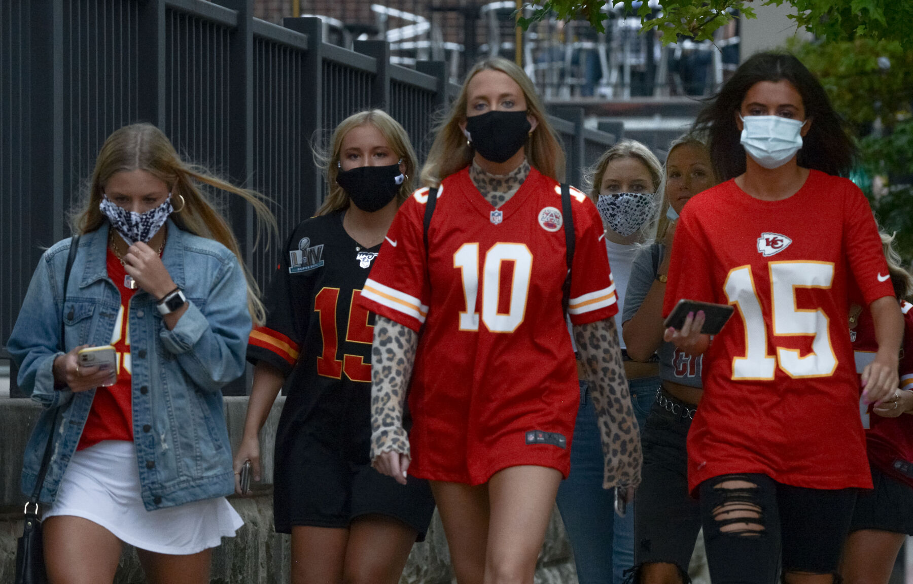 A group of young adults walks down Ninth Street wearing Chiefs jerseys